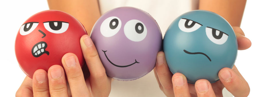 Hände halten drei Anti-Stress-Bälle mit Gesichtern